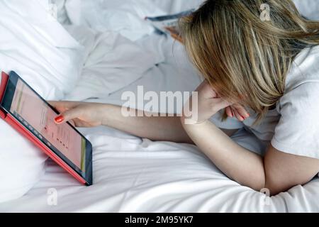 Woman using a tablet in bed. Digital shopping concept. Stock Photo