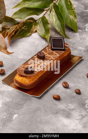 Chocolate glazed eclair with coffee custard on gold cardboard Stock Photo