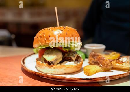 Healthy food, organic vegetarian burger with plant based falafel balls, vegan cheese, green lettuce and baked potatoes Stock Photo