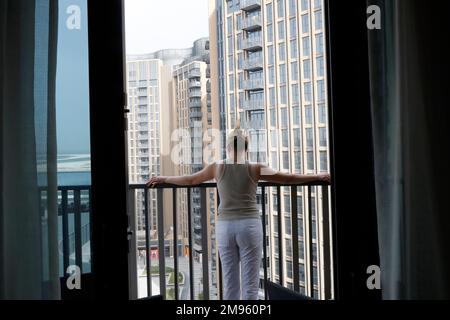 Back view of Young woman standing on balcony. Stock Photo