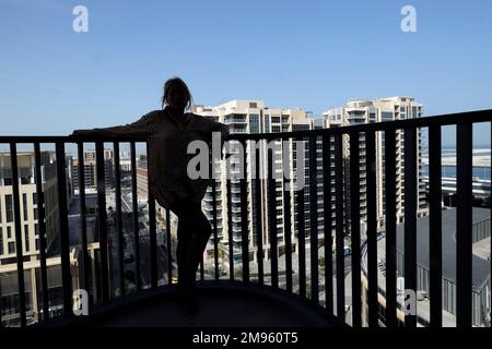 Back view of Young woman standing on balcony. Stock Photo