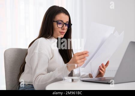 Happy millennial woman reading papers and working in the office. Stock Photo