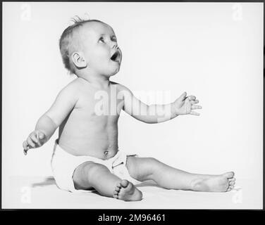 A baby wearing a towelling nappy looks up in astonishment Stock Photo