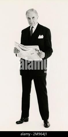 Full length portrait of a mature man posing in a suit, holding a newspaper. Stock Photo