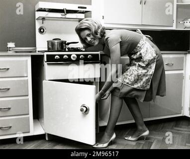 A housewife pops dinner in the oven. Stock Photo
