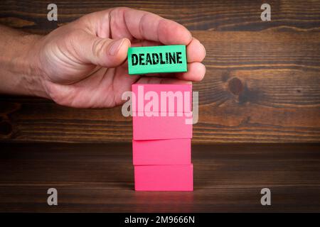 Deadline, business concept. Colorful wooden blocks in a pile on a wooden background. Stock Photo