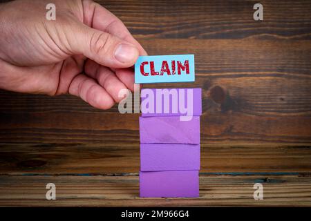 CLAIM CONCEPT. Colorful wooden blocks in a pile on a wooden background. Stock Photo