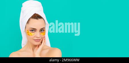 Eye patches, patch under eyes. young woman has collagen golden eye patches on face smile with towel. Beautiful woman isolated face portrait, banner Stock Photo