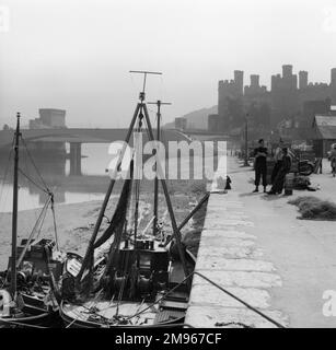 A wonderful, atmospheric view of Conwy Harbour, North Wales, with the silhouette of the Castle in the background. Photograph by Norman Synge Waller Budd Stock Photo