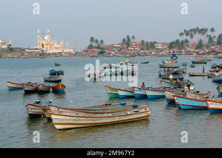 Fishing boats in the bay, with a mosque in the background, at Vishinjam, Trivandrum, Kerala State, India. Stock Photo