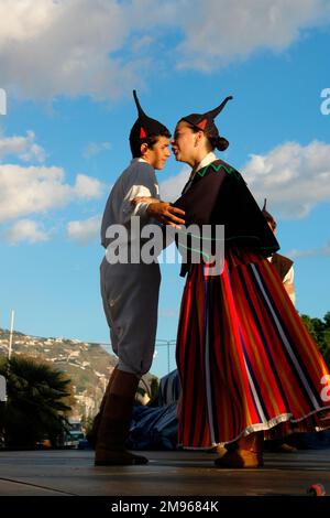 Two members of a Boa Nova folklore group, seen here dancing in Funchal, the capital city of Madeira. They are wearing traditional costume, including black skull caps with points. The woman wears a long striped skirt. Stock Photo