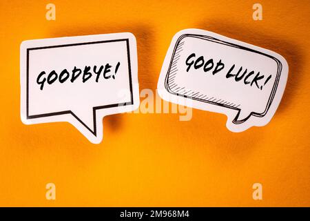 Goodbye and Good Luck. Text on speech bubbles. Yellow background. Stock Photo