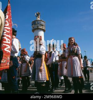 Scene at the Oktoberfest in Munich, Germany, with people in folk costume and the tower of the Lowenbrau Brewery in the background. Stock Photo