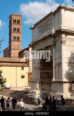 Side view of the Arch of Titus, with the tower of the Basilica di Massenzio (Basilica of Maxentius and Constantine) in the distance on the left.  The Arch was built in the 1st century AD to commemorate the Emperor Titus Flavius Vespasianus.  The basilica was completed in the 4th century -- it was originally used for legal purposes, but later became a place of worship. Stock Photo