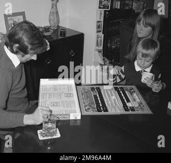 A man reading the rules of the board game Frogger, which was based on the popular arcade and video game of the same name and was brought out by Milton Bradley in 1981.  The board game version is for two players, who are allocated their own supply of frogs, logs and cars.  The purpose of the game is to move one's frogs to the other side of the board, moving logs and cars in order to block the other player.  Bonus points are awarded for landing on flies! Stock Photo