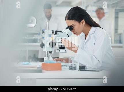 Science is about complex analytical processes. a young scientist using a microscope in a lab. Stock Photo