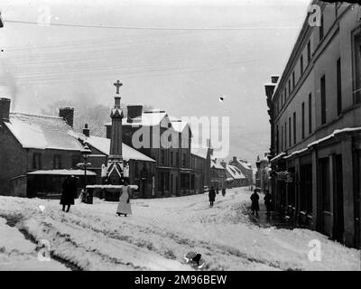 A view down the High Street from the Bear Hotel, in the town centre, Crickhowell, Powys, Mid Wales, with snow on the ground.  Recently installed telegraph wires can be seen above. Stock Photo