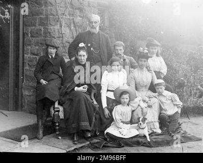 A large, middle class Edwardian family (adults,children and dog) pose for a group photograph outside their house, probably in the Mid Wales area. Stock Photo