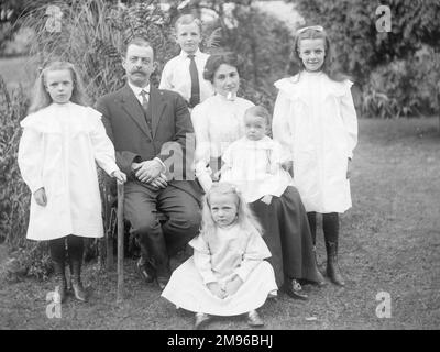 A middle class family (parents and five children) pose for their photo in a garden, probably in the Mid Wales area. Stock Photo