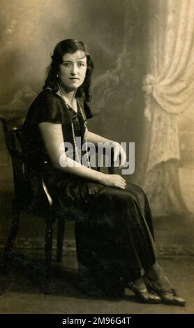 Woman wearing a long black satin dress and pearls, Stock Photo