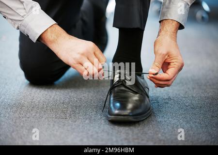 Looking sharp for a successful day. Closeup shot of an unrecognisable businessman tying his shoelaces in an office. Stock Photo