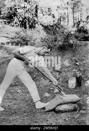 Soldier in side view, stabbing a stuffed sack with a bayoneted rifle, India. Stock Photo