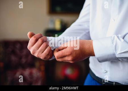 groom fastens cufflinks on the sleeve of a white shirt. Hands of a man close-up Stock Photo