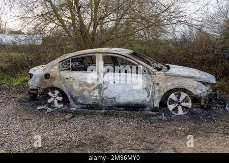 A burnt out modern car abandoned on waste ground in the UK Stock Photo