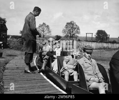 Holidaymakers on a miniature train in Seaford, East Sussex.  Two of the boys are wearing their school uniform. Stock Photo