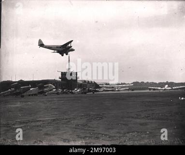 A de Havilland DH86, G-ADMY, comes in to land at Croydon Airport. Among the aircraft already on the ground are: de Havilland DH83 Fox Moth, G-ABUT; de Havilland DH84 Dragon I, G-ACIU; de Havilland DH90 Dragonfly, G-AEDH; de Havilland DH83 Fox Moth, G-ACFF; Handley Page HP42W, G-AAXC and Junkers Ju52/3m, OO-AGV, of Sabena. Stock Photo