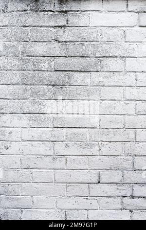 Vertical shot of old white painted rustic brick wall facade as background Stock Photo