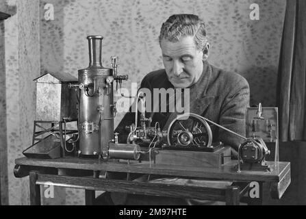 Man in his sitting room, working on a miniature steam engine. Stock Photo