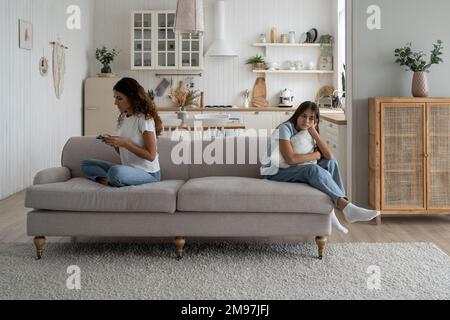 Focused busy woman mother using smartphone during family time child daughter at home Stock Photo