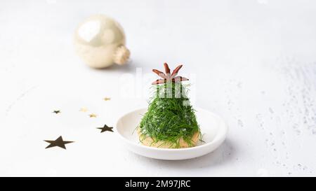 Christmas snack in the form of trees. Delicious cream cheese canapes with nuts, garlic and chopped dill on homemade puff cookies, decorated with a ani Stock Photo