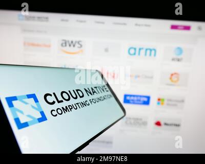 Smartphone with logo of Cloud Native Computing Foundation (CNCF) on screen in front of website. Focus on center-left of phone display. Stock Photo