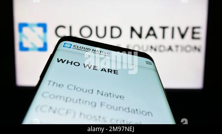Mobile phone with website of Cloud Native Computing Foundation (CNCF) on screen in front of business logo. Focus on top-left of phone display. Stock Photo