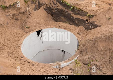 Concrete sewer rings in the ground. Construction or repair of sewerage on an industrial site. Stock Photo