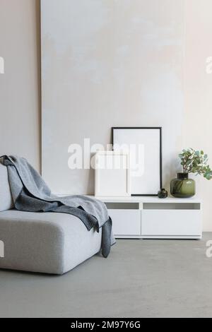 Modern ceramic vase two empty picture frames on a sideboard next to a sofa Stock Photo