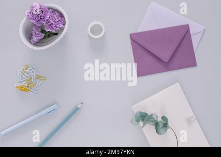 Overhead view of purple carnation flower heads, envelopes and assorted stationery on a table Stock Photo