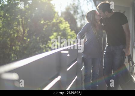 A couple standing on a balcony kissing, France Stock Photo