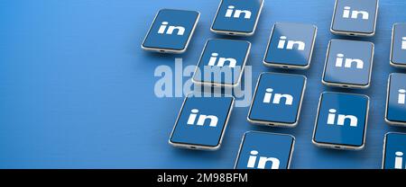 Logos of the business social media platform LinkedIn displayed on smartphones hovering over a blue background. Copy space Stock Photo
