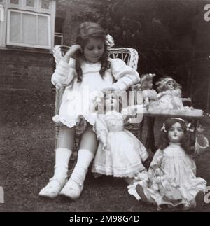 Little girl (Violet Auerbach) with her dolls in a back garden. Stock Photo