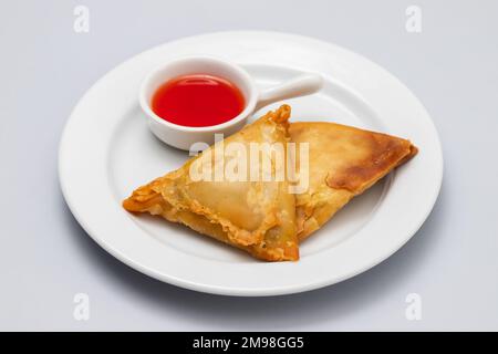 Two samosas with meat and vegetables on white plate Stock Photo