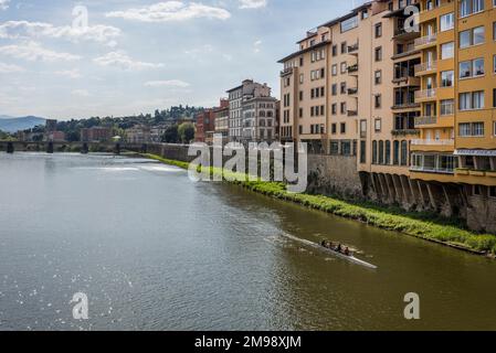 Florence, Italy - April, 15, 2022: Group rowing along the Arno River with city in the background Stock Photo
