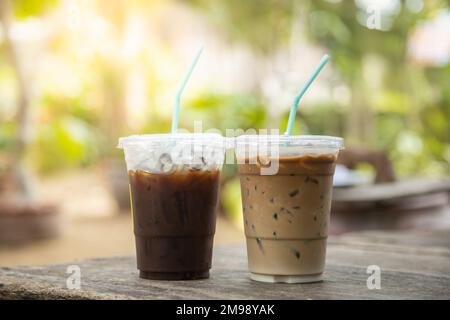 https://l450v.alamy.com/450v/2m98yak/closeup-of-takeaway-plastic-cup-of-iced-black-coffee-americano-and-coffee-latte-on-wooden-table-with-green-nature-background-2m98yak.jpg