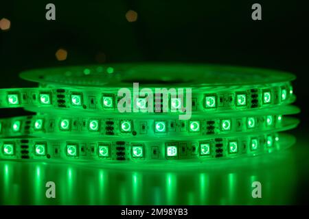 Roll of chasing LED strip with bright neon green lamps placed on table in dark room Stock Photo