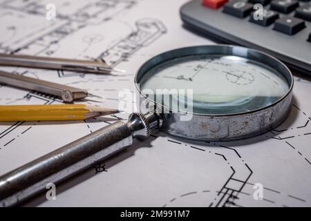 Silver metal magnifying glass on blueprint background. Stock Photo