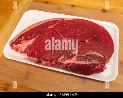 Raw uncooked meat. Sirloin steak in a butcher tray on a wooden cutting board. Stock Photo