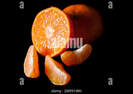 Studio shot of a halved orange with three orange wedges. Stock Photo