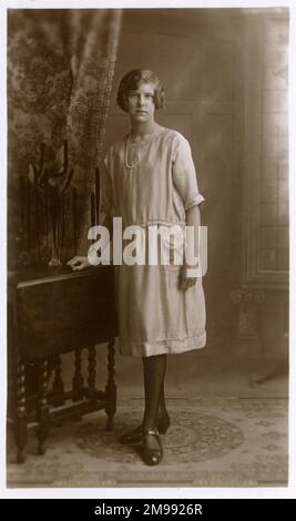 Studio Portrait of a woman in elegant shift dress and string of pearls - note the attractive folding table she is resting against... Stock Photo